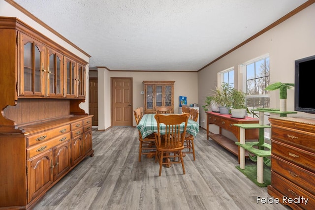 dining area with ornamental molding, a textured ceiling, and light hardwood / wood-style floors