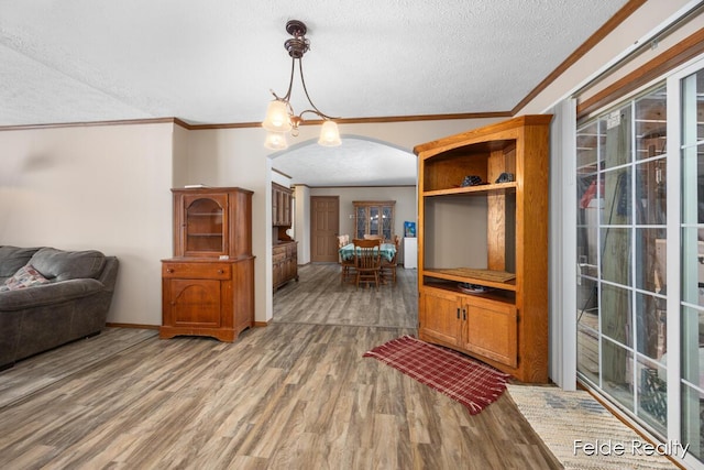 living room featuring crown molding, wood-type flooring, a chandelier, and a textured ceiling