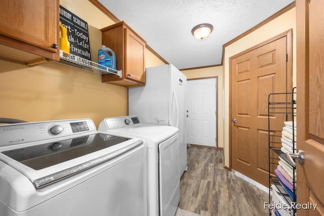 laundry area featuring crown molding, dark wood-type flooring, cabinets, washer and dryer, and a textured ceiling