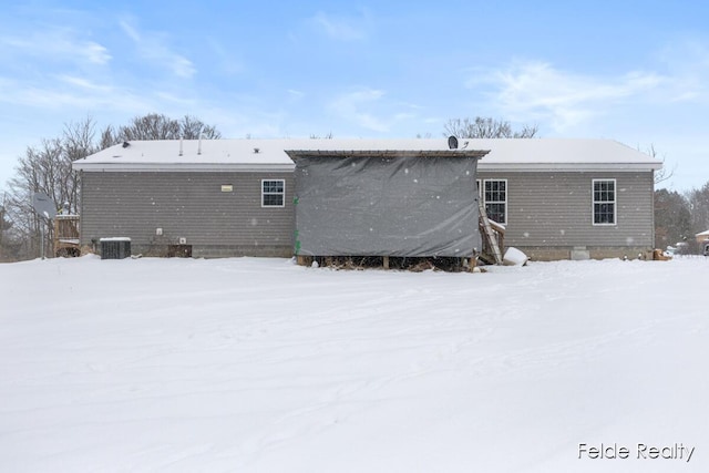 snow covered house featuring cooling unit