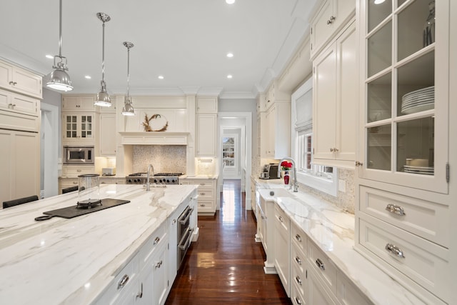 kitchen featuring light stone countertops, white cabinetry, glass insert cabinets, and stainless steel microwave