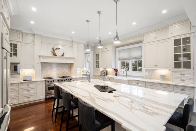 kitchen featuring appliances with stainless steel finishes, a breakfast bar area, a large island, and glass insert cabinets