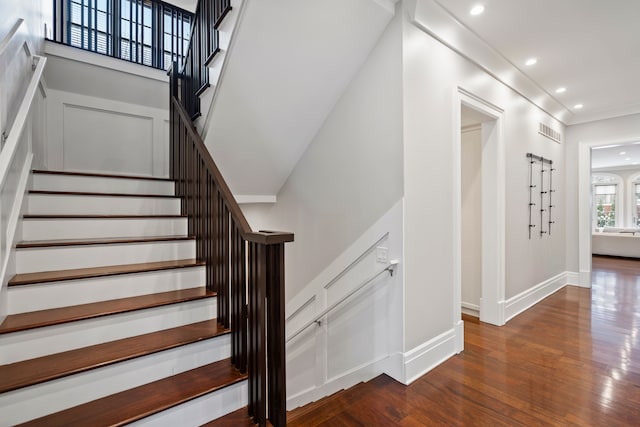 stairway with recessed lighting, wood finished floors, visible vents, baseboards, and ornamental molding