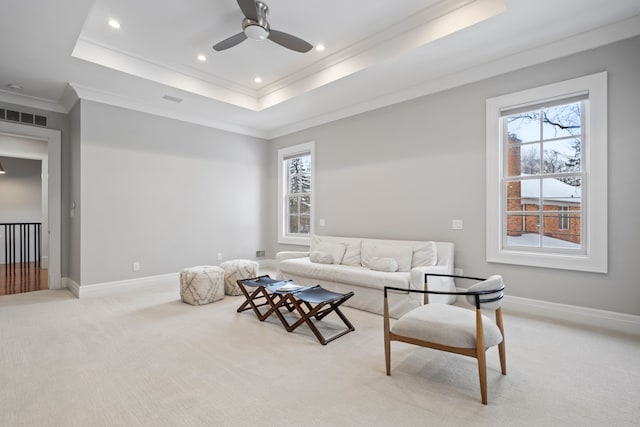 living area featuring light carpet, a raised ceiling, visible vents, and baseboards