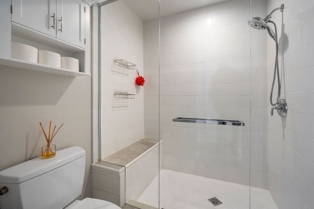 bathroom featuring toilet and a tile shower