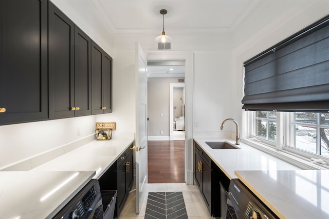 kitchen featuring light countertops, hanging light fixtures, a sink, and dark cabinetry