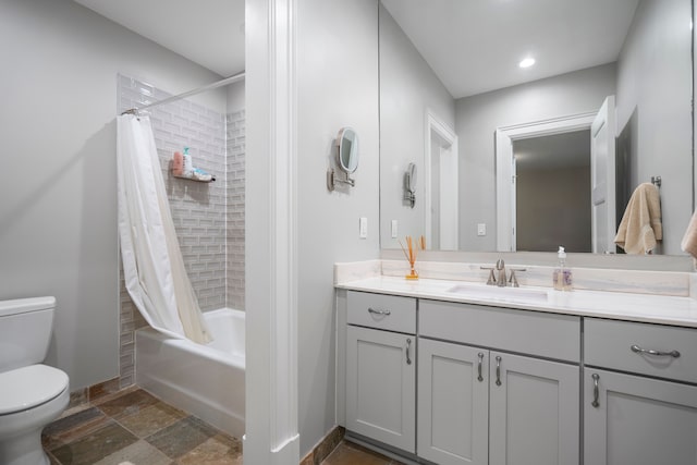 full bath featuring toilet, vanity, baseboards, stone finish floor, and shower / bath combo with shower curtain