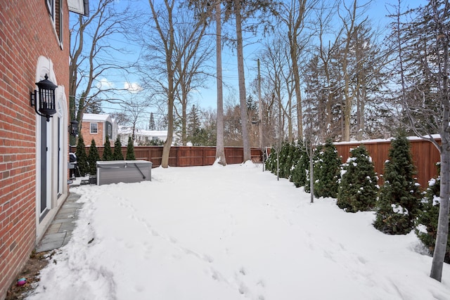 yard covered in snow featuring a fenced backyard and a hot tub