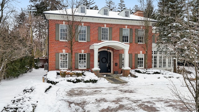 georgian-style home with central AC and brick siding