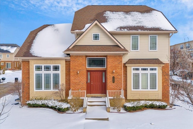 view of front of home with a shingled roof and brick siding