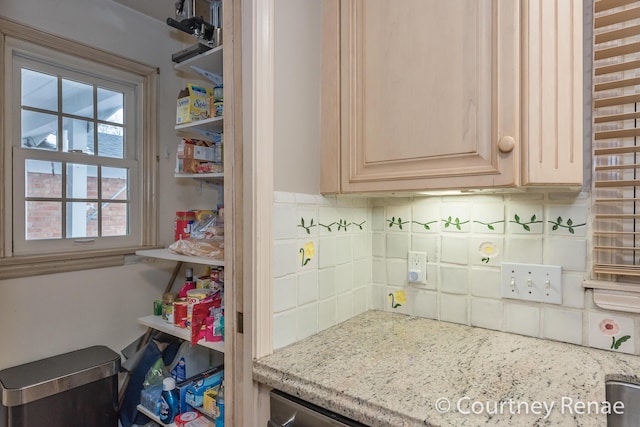 interior space with light brown cabinets, light stone counters, and decorative backsplash