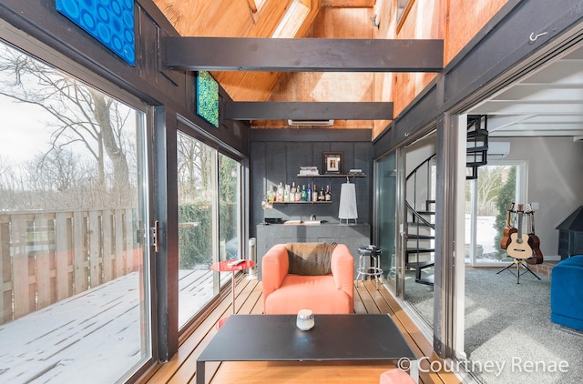 interior space featuring lofted ceiling with beams, a healthy amount of sunlight, a wall mounted air conditioner, and bar area