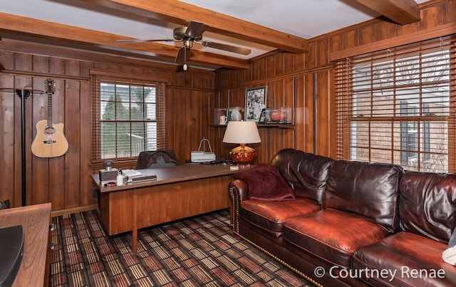 home office featuring ceiling fan, wooden walls, and beamed ceiling