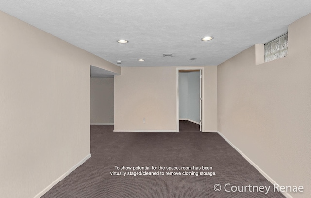 unfurnished room with a textured ceiling and dark colored carpet