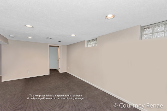 basement featuring a textured ceiling and dark colored carpet