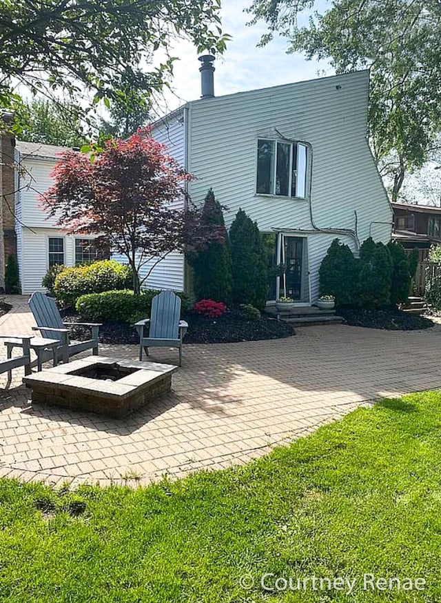 back of house with an outdoor fire pit, a patio area, and a lawn