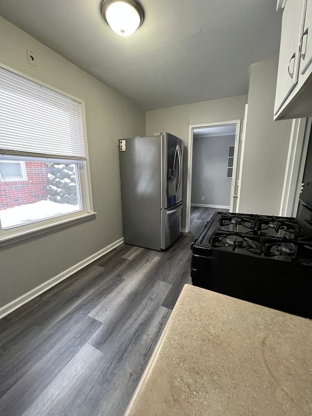 kitchen featuring white cabinets, black range with gas cooktop, dark hardwood / wood-style flooring, and stainless steel refrigerator with ice dispenser