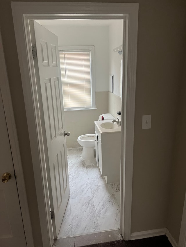 bathroom with vanity, tile walls, and toilet