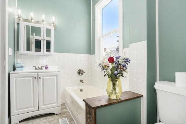 bathroom featuring tile walls, a tub to relax in, vanity, and toilet