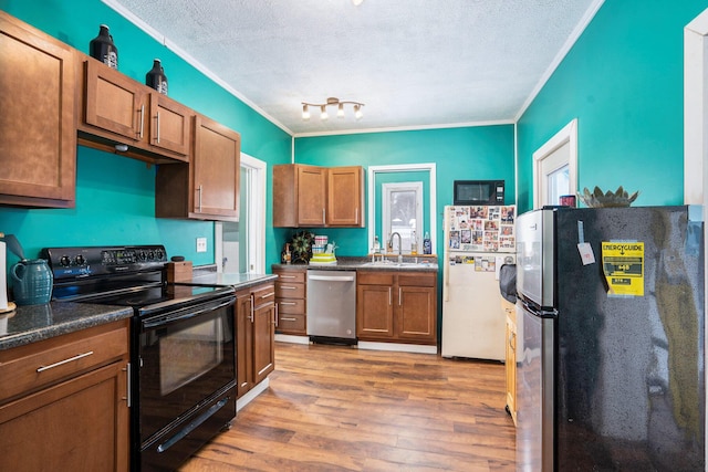 kitchen with appliances with stainless steel finishes, sink, a textured ceiling, and light wood-type flooring