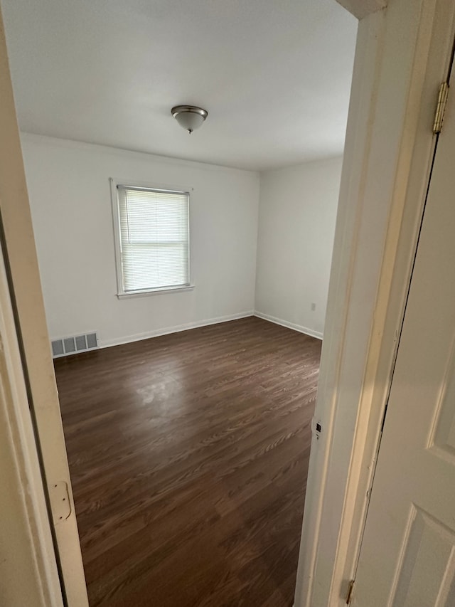 unfurnished room with dark wood-type flooring