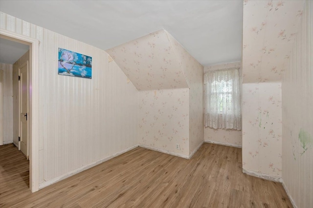 additional living space with lofted ceiling and light hardwood / wood-style flooring