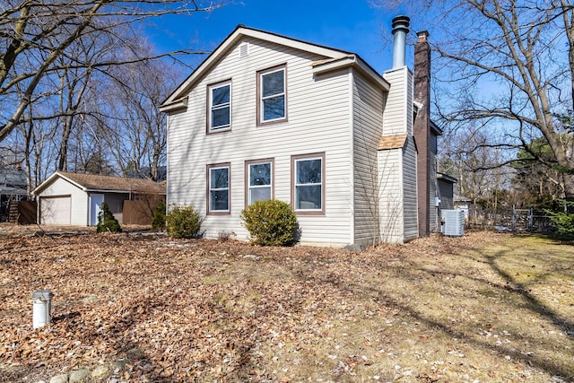 view of front of home with a chimney, a detached garage, and an outdoor structure