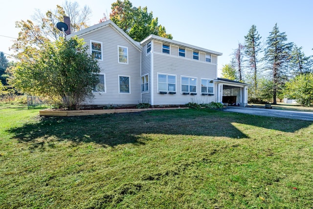 back of property with a carport and a lawn