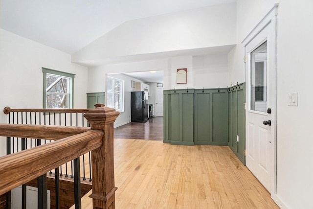 hallway with vaulted ceiling and light wood-type flooring