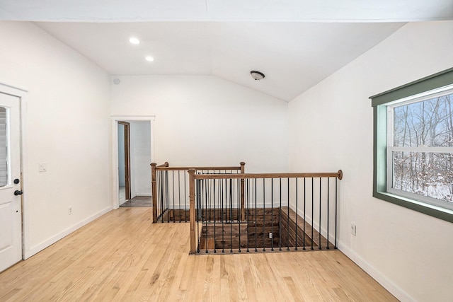 hallway with vaulted ceiling and light hardwood / wood-style floors