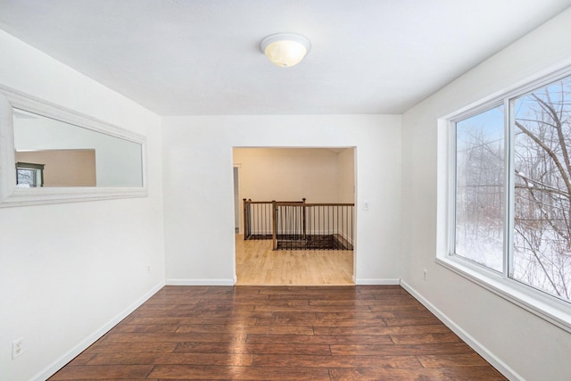 empty room featuring dark wood-type flooring and a healthy amount of sunlight