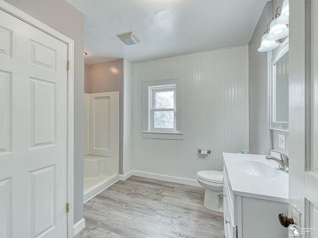 bathroom with hardwood / wood-style flooring, a shower, vanity, and toilet