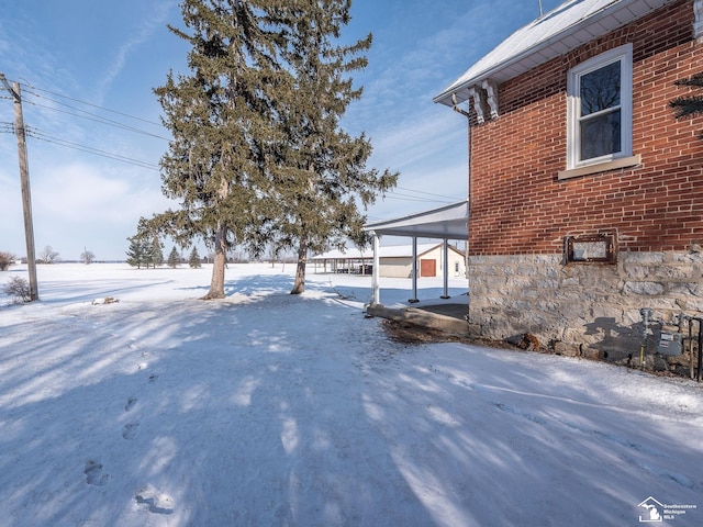 snowy yard with a carport