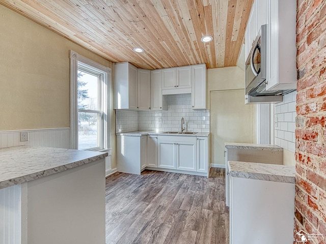 kitchen with sink, white cabinets, decorative backsplash, wood ceiling, and light wood-type flooring