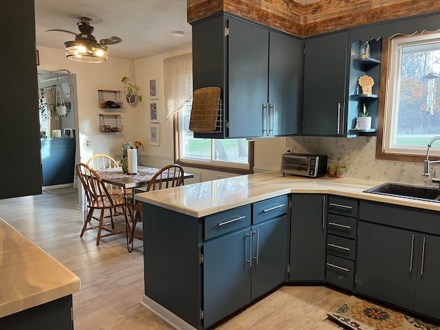 kitchen featuring light hardwood / wood-style floors, sink, backsplash, and ceiling fan