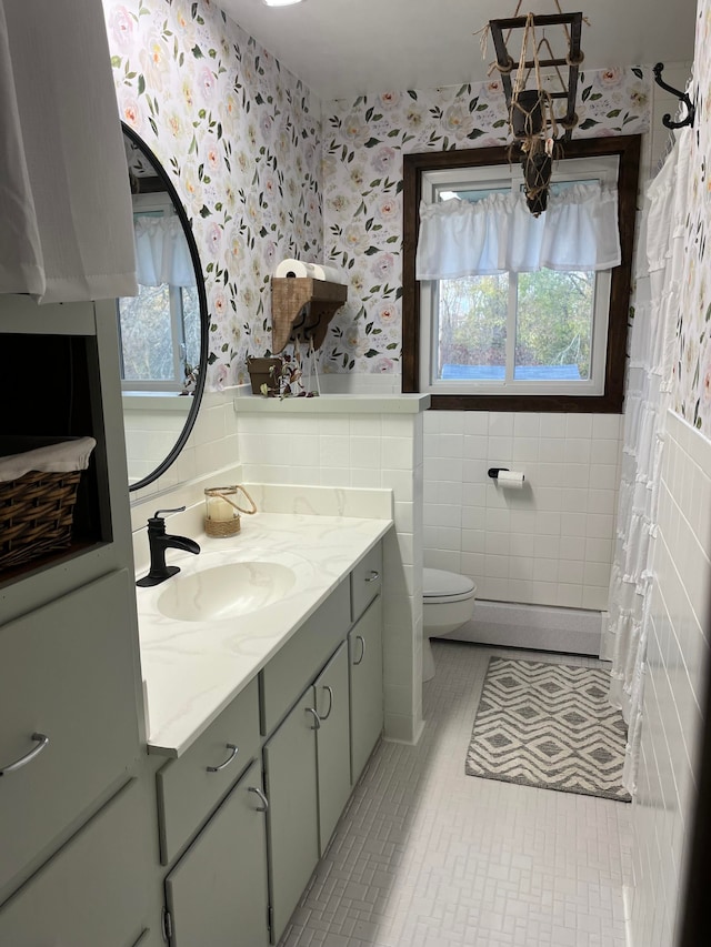 bathroom with tile walls, vanity, toilet, a baseboard radiator, and tile patterned floors