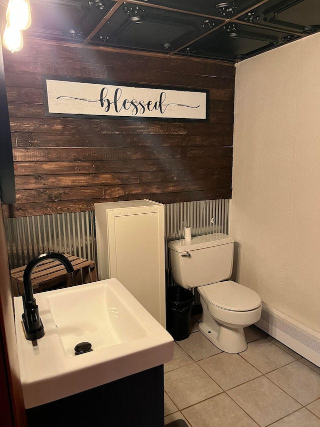 bathroom featuring sink, toilet, tile patterned floors, and wooden walls