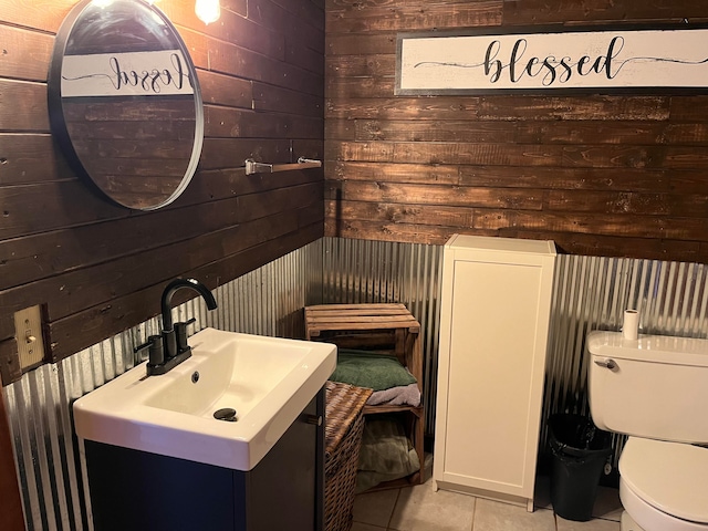 bathroom featuring wood walls, sink, tile patterned flooring, and toilet