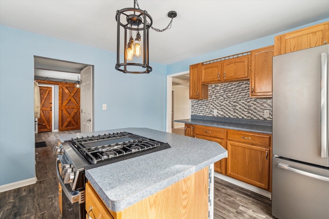 kitchen featuring pendant lighting, dark wood-type flooring, stainless steel appliances, a center island, and decorative backsplash