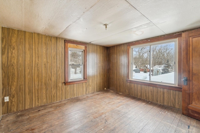 unfurnished room featuring hardwood / wood-style floors and wood walls