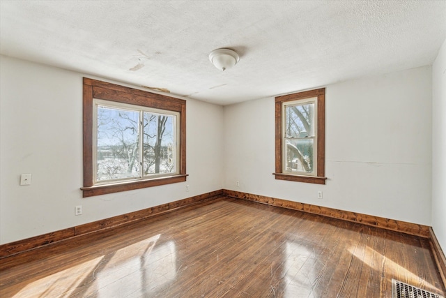 spare room featuring hardwood / wood-style floors, a textured ceiling, and a healthy amount of sunlight