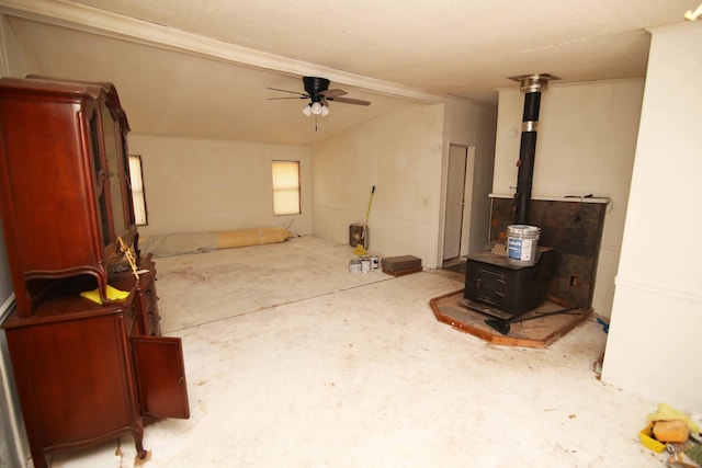 living room featuring vaulted ceiling, a wood stove, and ceiling fan