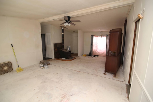 unfurnished living room featuring lofted ceiling with beams, ceiling fan, and a wood stove