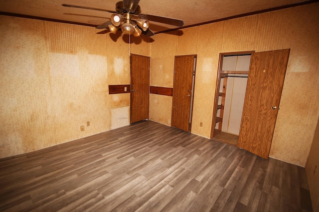 unfurnished bedroom with ceiling fan, dark hardwood / wood-style flooring, and two closets