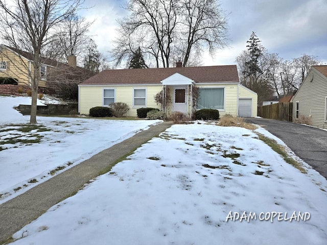 view of front of home with driveway, a detached garage, and fence