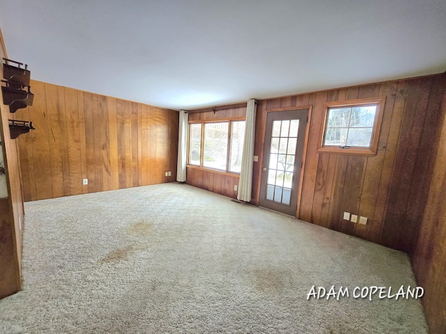 carpeted spare room featuring wood walls