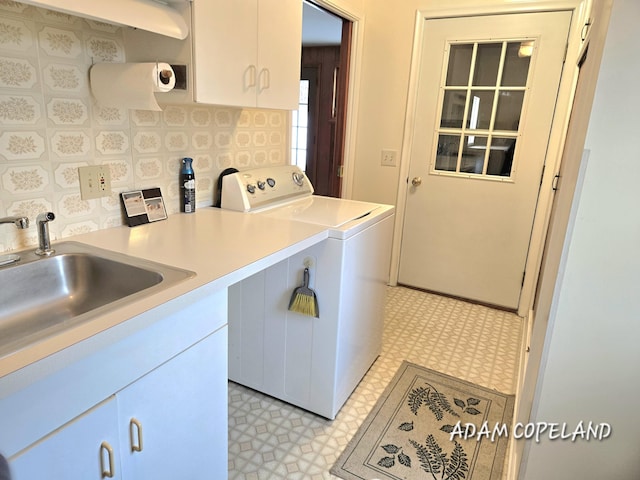 clothes washing area with cabinets, sink, and washer and dryer