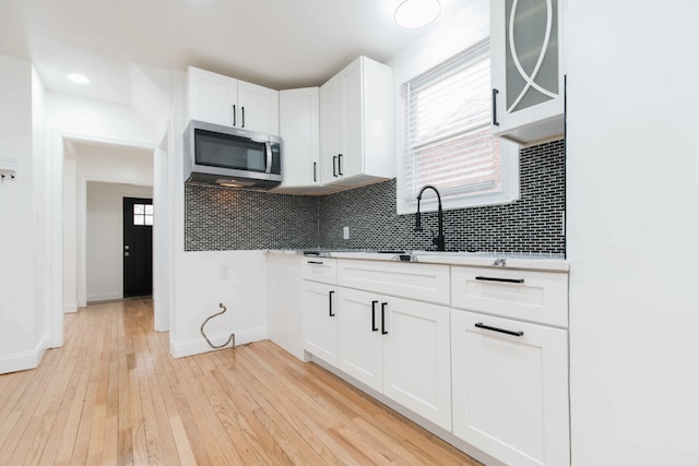 kitchen with white cabinetry, plenty of natural light, decorative backsplash, and light hardwood / wood-style flooring