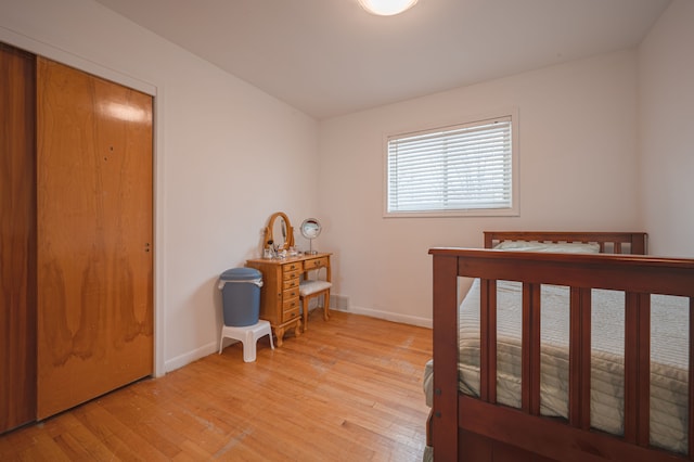 bedroom with light hardwood / wood-style floors and a closet