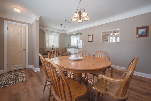 dining area featuring dark wood-type flooring and a notable chandelier